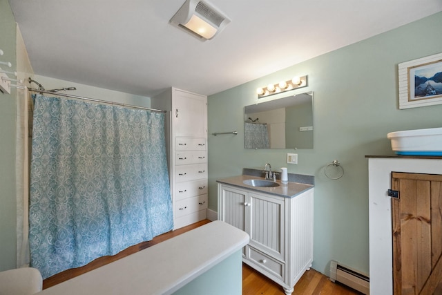 full bathroom with wood finished floors, baseboard heating, vanity, and visible vents