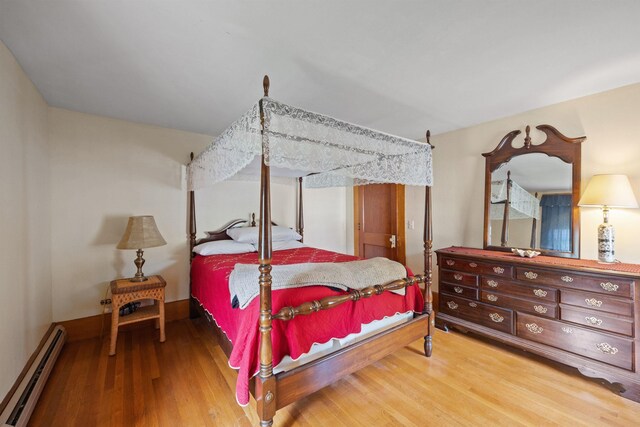 bedroom featuring baseboard heating and wood finished floors