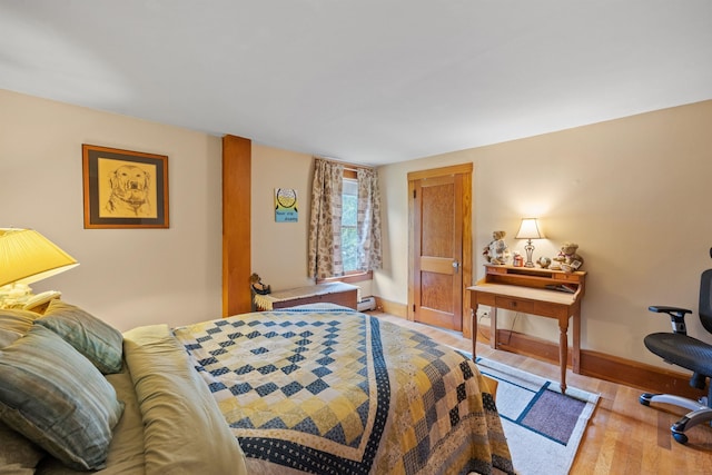 bedroom with a baseboard heating unit, baseboards, and wood finished floors