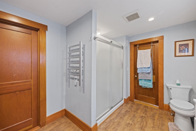 bathroom featuring visible vents, toilet, a shower stall, wood finished floors, and baseboards