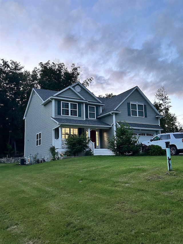 view of front facade featuring covered porch, a yard, and a garage