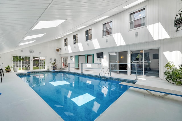 view of pool with a skylight and a diving board