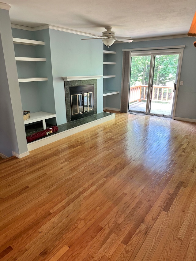 unfurnished living room featuring ceiling fan, light hardwood / wood-style floors, ornamental molding, and built in shelves