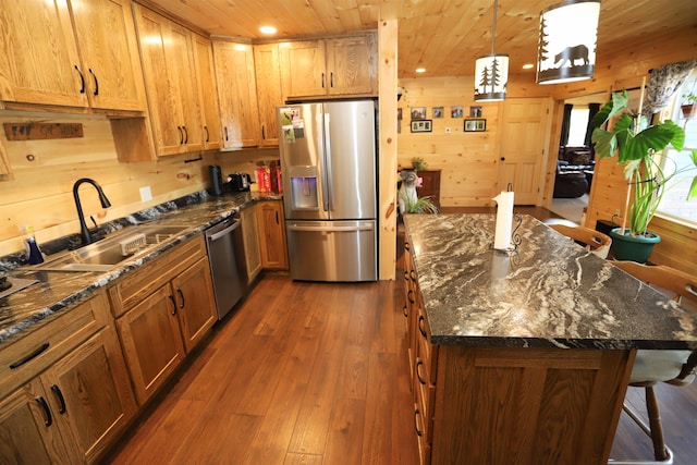 kitchen featuring wood walls, a center island, sink, dark hardwood / wood-style flooring, and appliances with stainless steel finishes