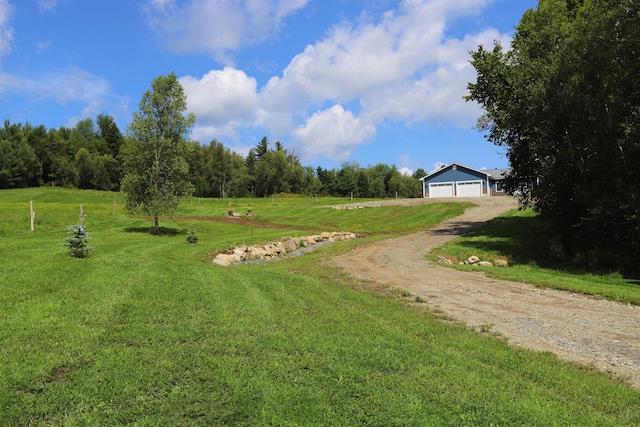 view of yard with a garage, a rural view, and an outbuilding