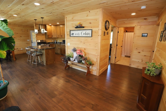 kitchen with decorative light fixtures, wooden walls, wooden ceiling, and dark wood-type flooring