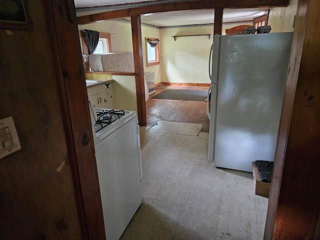 kitchen with white gas stove, fridge, and light hardwood / wood-style flooring