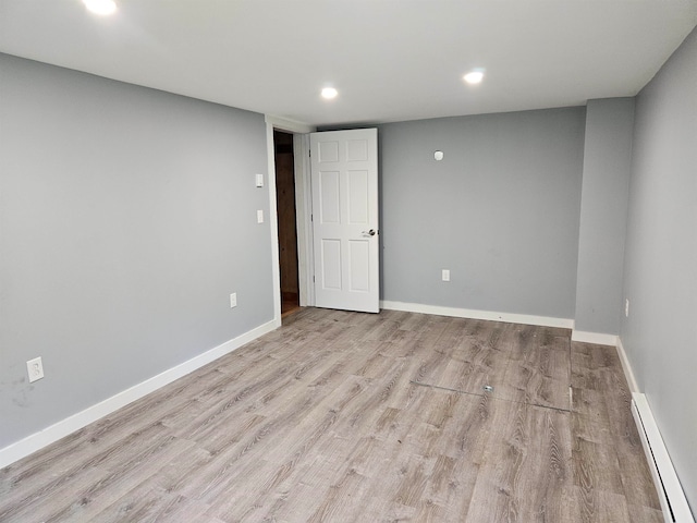 spare room with light wood-type flooring and a baseboard heating unit