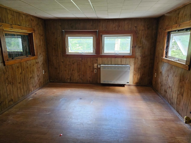 spare room featuring hardwood / wood-style flooring, plenty of natural light, and wooden walls