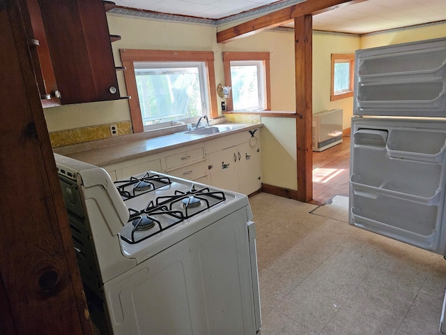 kitchen with white range with gas stovetop, white cabinetry, and sink