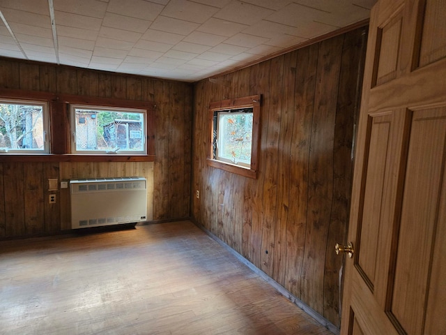 spare room featuring light hardwood / wood-style flooring, radiator, and wood walls