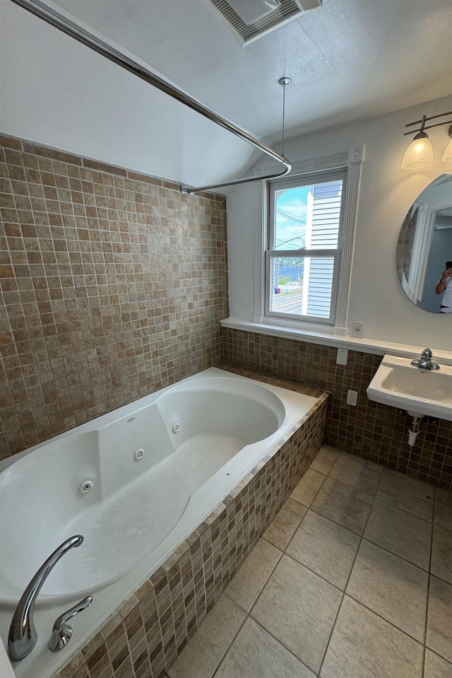 bathroom with sink, a relaxing tiled tub, tile patterned floors, and tile walls