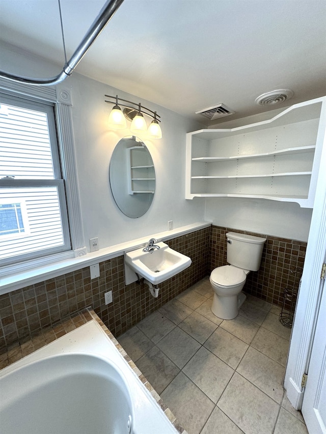 bathroom with tiled bath, sink, tile patterned floors, tile walls, and toilet