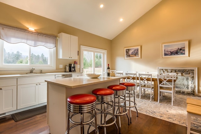 kitchen with sink, a center island, dark hardwood / wood-style floors, white cabinets, and lofted ceiling