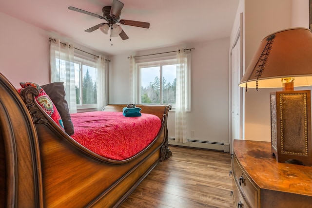 bedroom featuring light hardwood / wood-style flooring, ceiling fan, and a baseboard heating unit