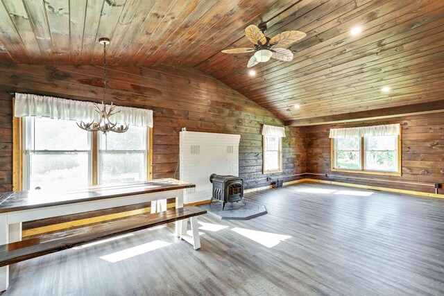 unfurnished living room with hardwood / wood-style flooring, wooden walls, wooden ceiling, and a wood stove