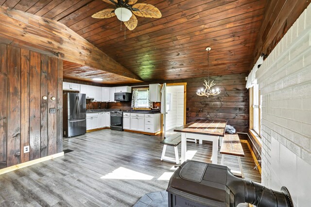 interior space with wood walls, ceiling fan with notable chandelier, wood ceiling, vaulted ceiling, and hardwood / wood-style flooring