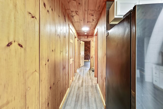 hallway with light wood-type flooring and wooden walls