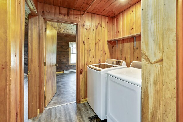 laundry room featuring wood walls, separate washer and dryer, a baseboard radiator, hardwood / wood-style flooring, and wood ceiling