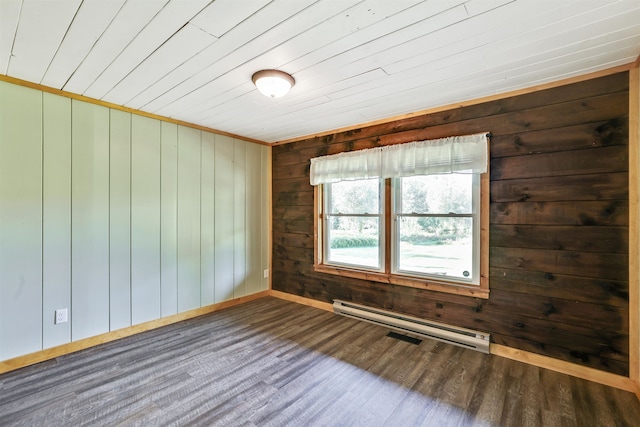 spare room with wooden walls, a baseboard heating unit, and dark wood-type flooring