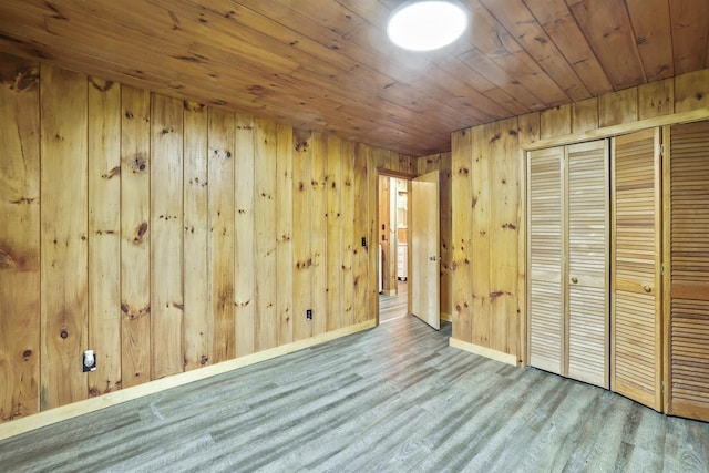 unfurnished bedroom with wood ceiling, a closet, wood walls, and light wood-type flooring