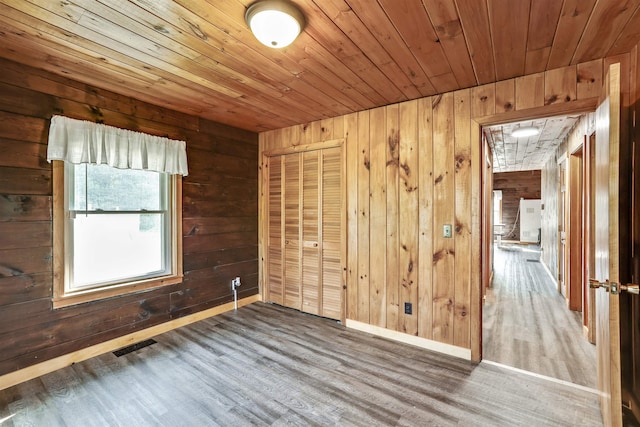 empty room with wood walls, wood ceiling, and wood-type flooring