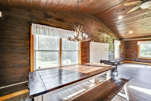 unfurnished dining area featuring wooden walls, ceiling fan with notable chandelier, wood-type flooring, wood ceiling, and vaulted ceiling