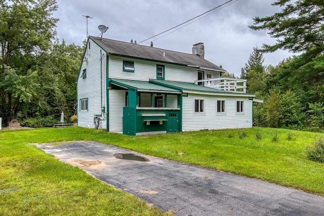 view of front of house featuring a front yard, aphalt driveway, and a chimney