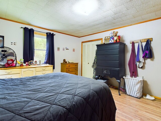 bedroom with light hardwood / wood-style flooring, a closet, and ornamental molding