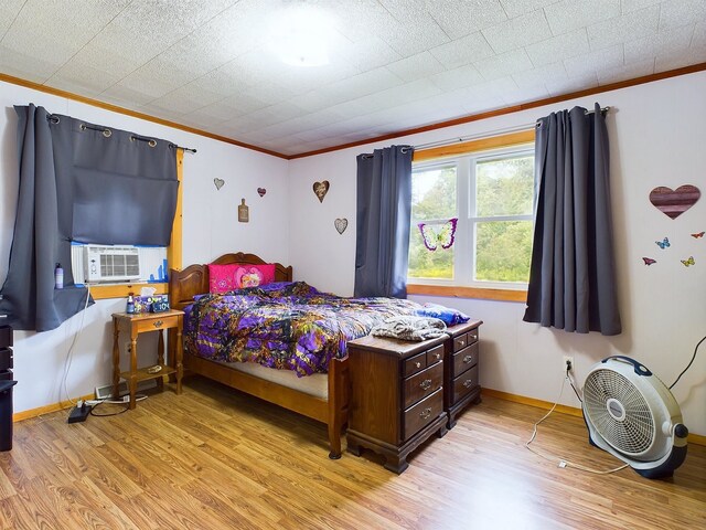 bedroom with light wood-type flooring, crown molding, and cooling unit