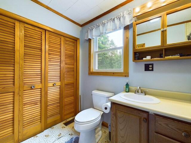 bathroom featuring tile patterned flooring, crown molding, vanity, and toilet