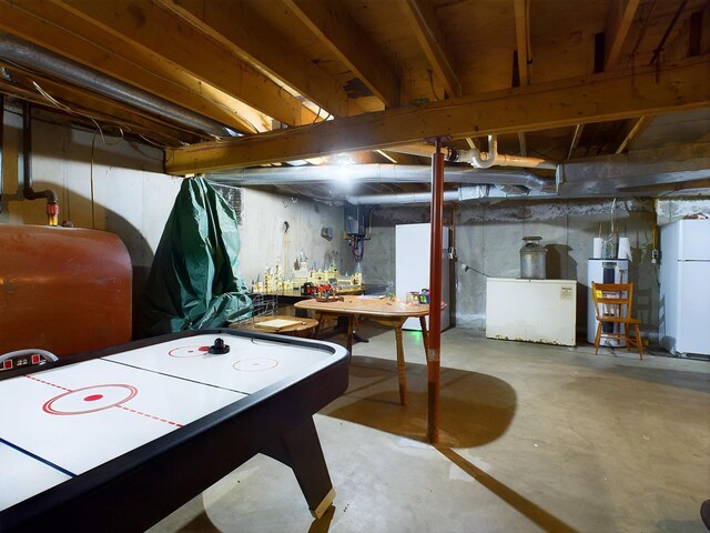 basement featuring white refrigerator and refrigerator