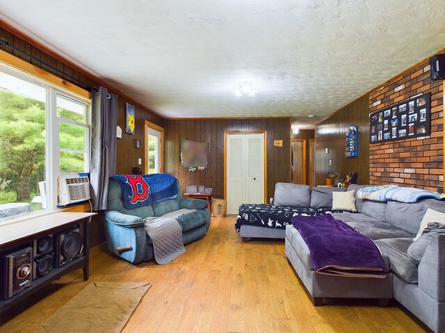 living room with wooden walls, cooling unit, and light hardwood / wood-style floors