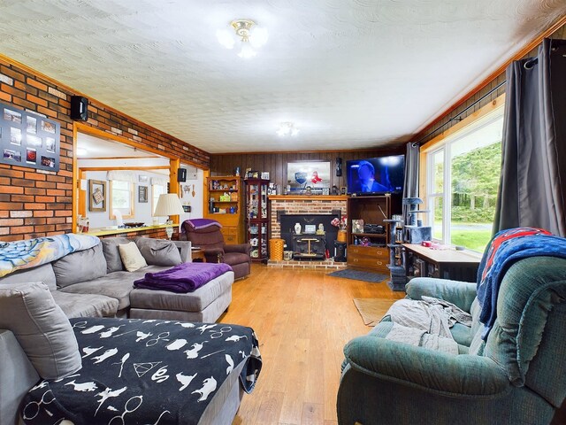 living room featuring hardwood / wood-style floors, brick wall, a textured ceiling, wooden walls, and a brick fireplace