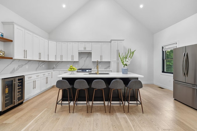 kitchen with beverage cooler, stainless steel fridge, backsplash, and light hardwood / wood-style flooring