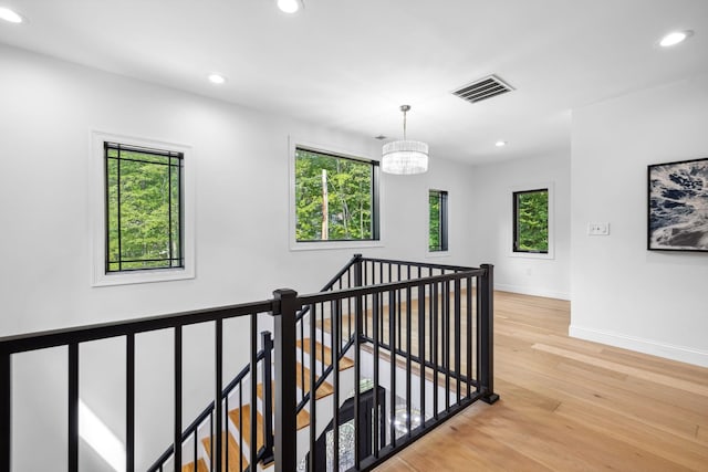 hall featuring light hardwood / wood-style flooring and an inviting chandelier