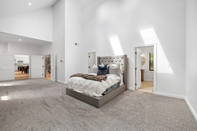 carpeted bedroom with a walk in closet, high vaulted ceiling, and connected bathroom