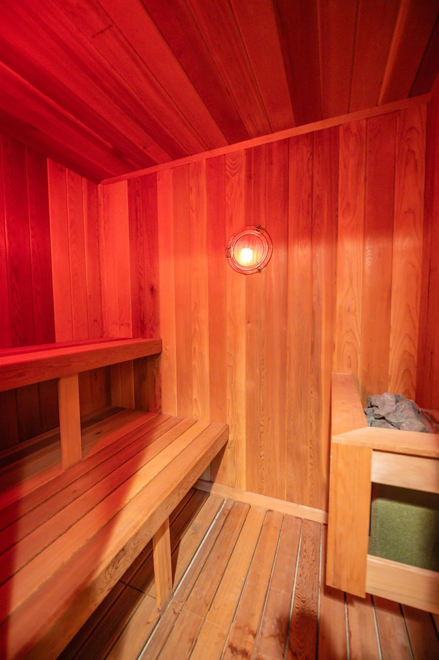 view of sauna / steam room featuring wood-type flooring, wooden ceiling, and wooden walls