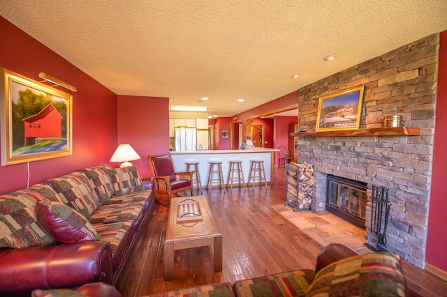 living room with a fireplace, a textured ceiling, and hardwood / wood-style floors