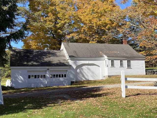 view of front of property with a garage, roof with shingles, a front yard, and fence