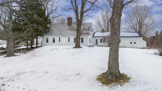 view of front of property with a standing seam roof, a chimney, and metal roof