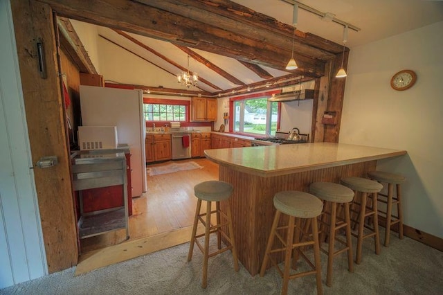 kitchen featuring a breakfast bar area, lofted ceiling with beams, stainless steel dishwasher, brown cabinetry, and a peninsula