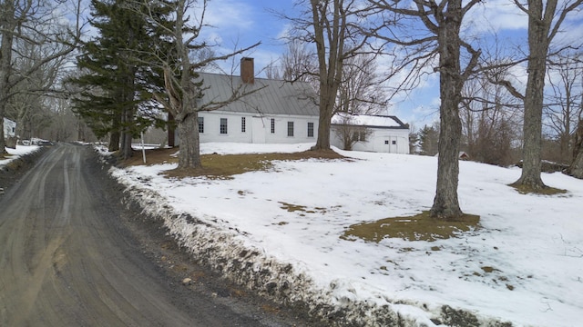 view of front of house with a garage, metal roof, and a chimney