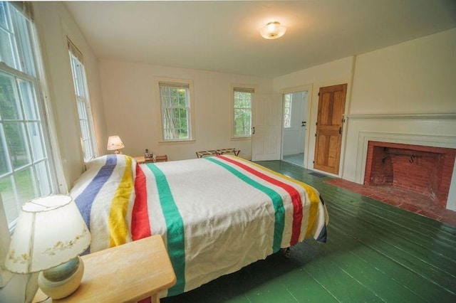 bedroom featuring a fireplace with flush hearth and dark wood-type flooring