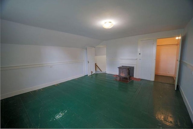 unfurnished room featuring dark wood-style flooring, vaulted ceiling, and baseboards