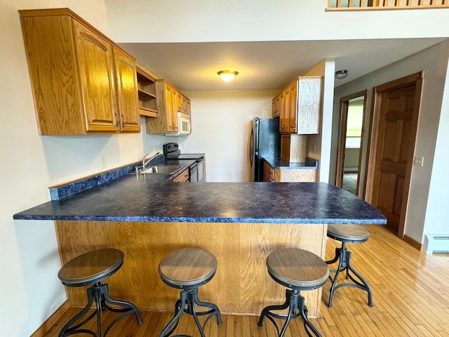 kitchen featuring electric stove, dark countertops, a peninsula, and freestanding refrigerator