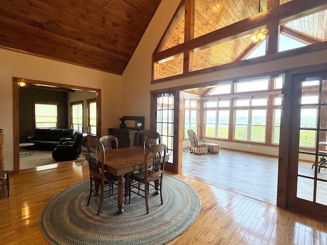 dining space with high vaulted ceiling, wooden ceiling, beam ceiling, and light wood-style floors