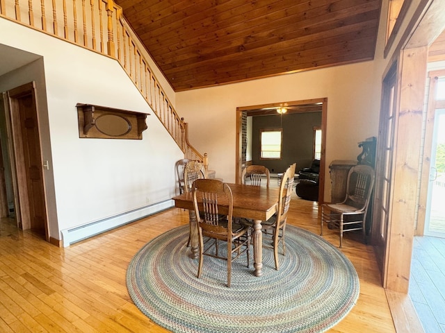 dining room featuring high vaulted ceiling, a baseboard radiator, wooden ceiling, light wood-style flooring, and stairway