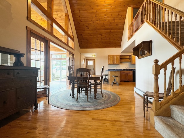 dining space featuring wooden ceiling, light wood-style floors, stairway, and high vaulted ceiling