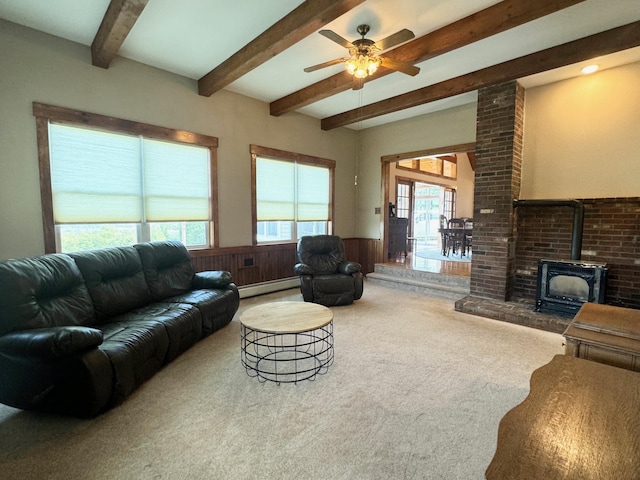 living area with wainscoting, a wood stove, baseboard heating, carpet floors, and beam ceiling